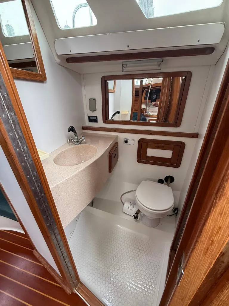 Slide: The Image of 1998 Catalina 42Mk 2 yacht bathroom with sink, toilet, and mirror, featuring wood accents. - 8