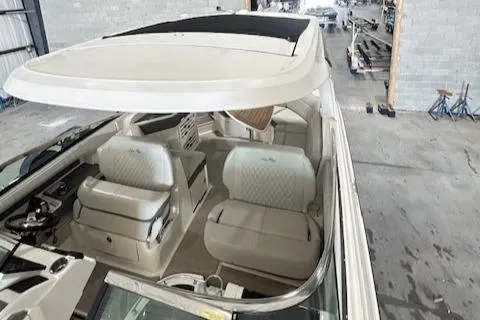 Slide: The Image of 2021 Sea Ray SLX 310 boat interior with white seating and helm, in a warehouse setting. - 14
