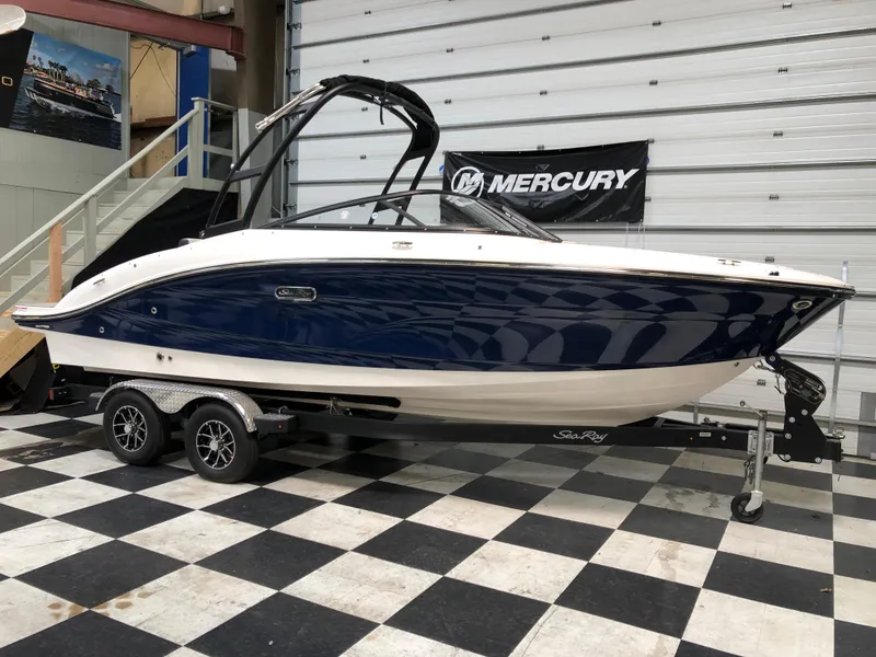 The Image of 2025 Sea Ray SPX 210 boat on trailer in showroom with checkered floor. - 1