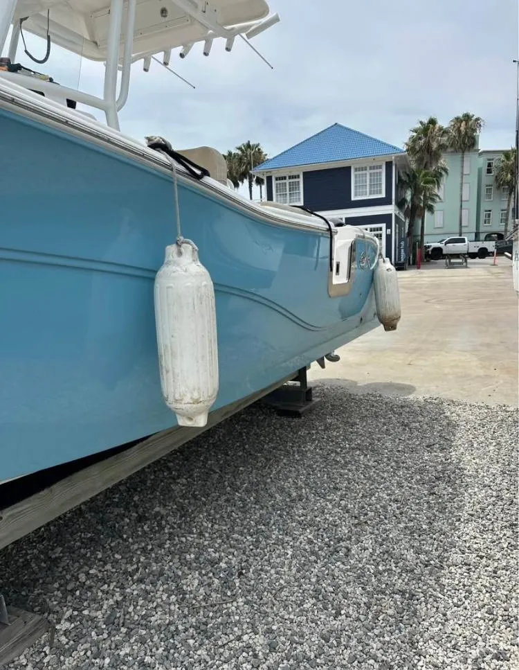 Slide: The Image of 2021 Sea Fox 268 Commander boat on gravel, with blue hull and dock fenders. - 3