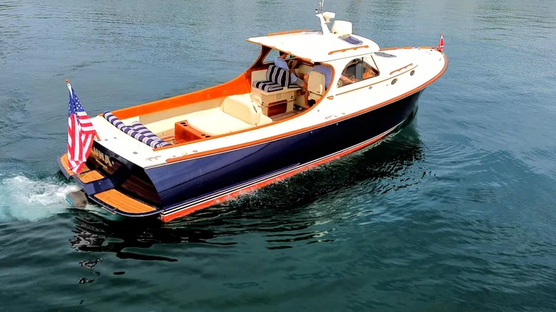 Slide: The Image of Hinckley Picnic Boat 2000 cruising on water, featuring elegant design and American flag. - 1