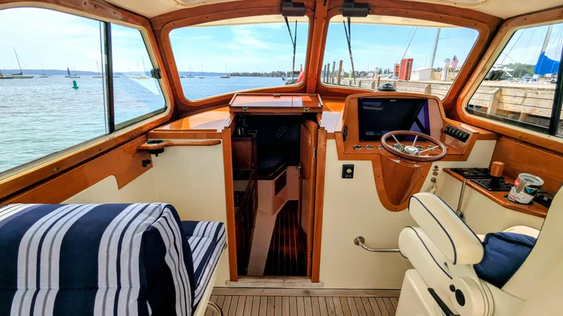 Slide: The Image of Interior of a 2000 Hinckley Picnic Boat with striped seating and wooden helm. - 6