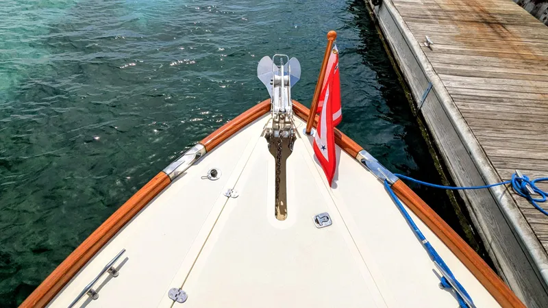 Slide: The Image of Bow of a 2000 Hinckley Picnic Boat docked, featuring a flag and anchor chain. - 13