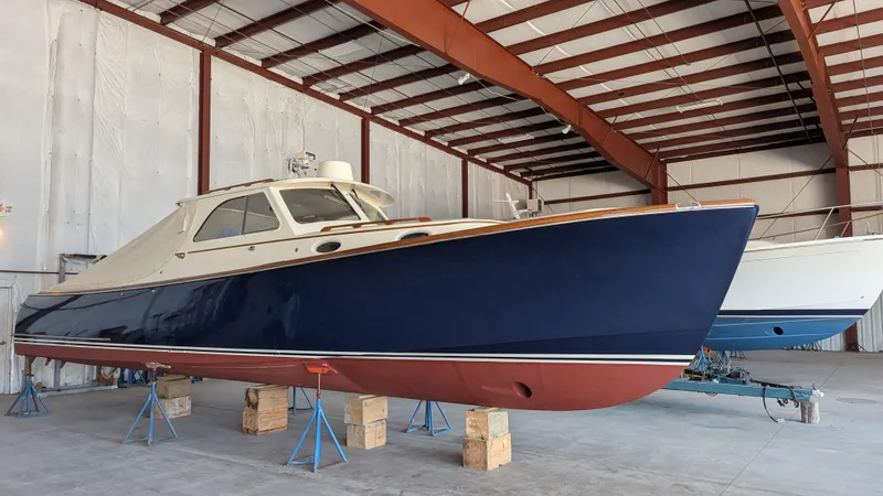 Slide: The Image of 2000 Hinckley Picnic Boat in storage, blue hull, indoor warehouse setting. - 19
