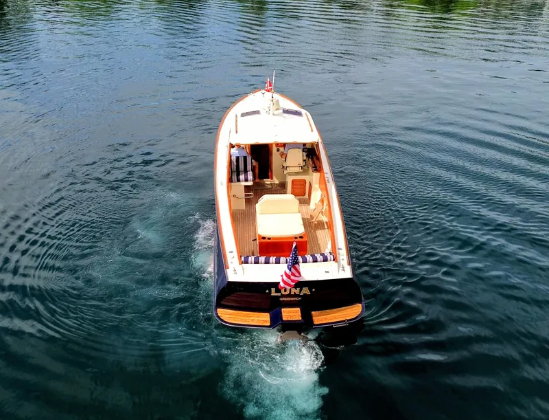 Slide: The Image of Hinckley Picnic Boat 2000 cruising on calm water, rear view with American flag. - 2