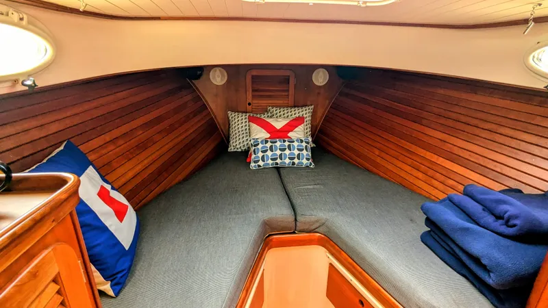 Slide: The Image of Cozy cabin interior of 2000 Hinckley Picnic Boat with wooden paneling and nautical-themed pillows. - 10