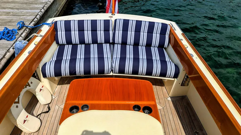 Slide: The Image of 2000 Hinckley Picnic Boat interior with striped seating and wooden table by the water. - 12