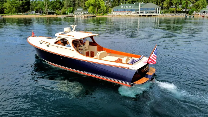 Slide: The Image of Hinckley Picnic Boat 2000 cruising on a serene lake with lush greenery in the background. - 17