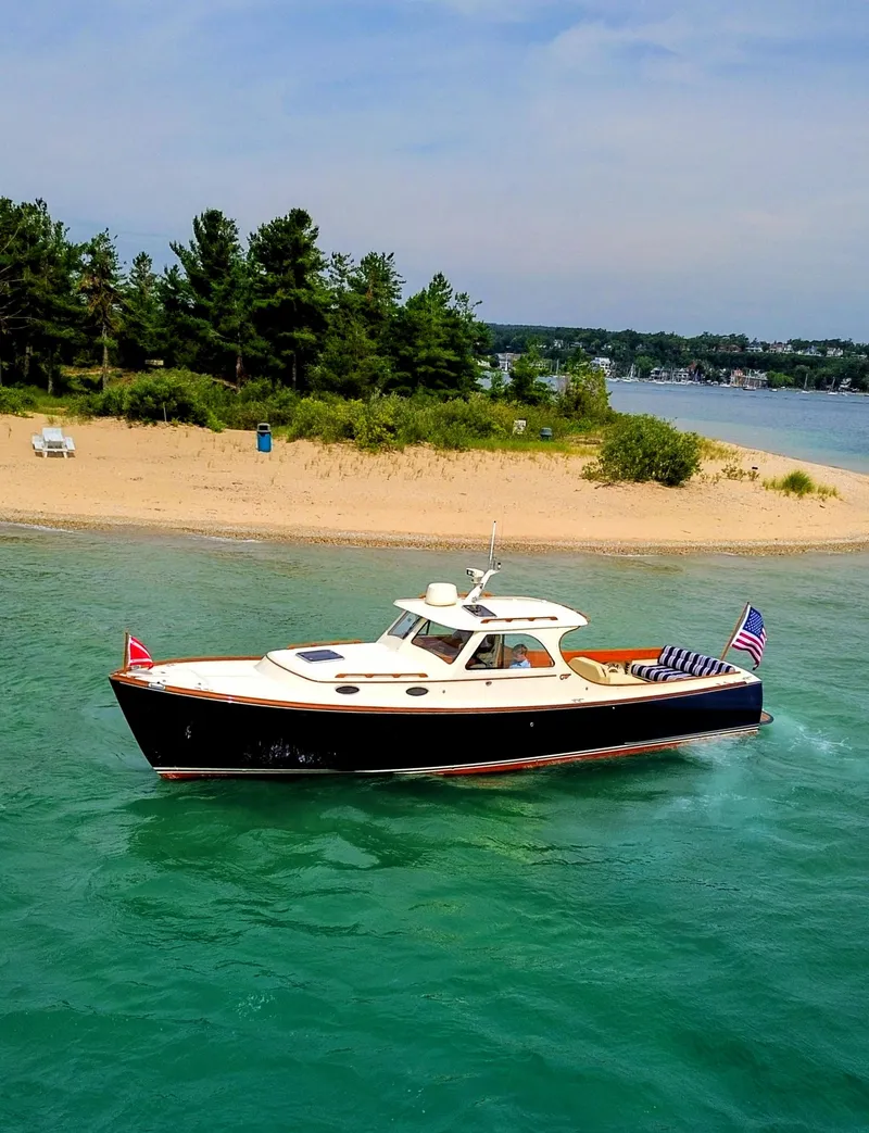 Slide: The Image of Hinckley Picnic Boat 2000 cruising near a sandy beach with lush greenery. - 18