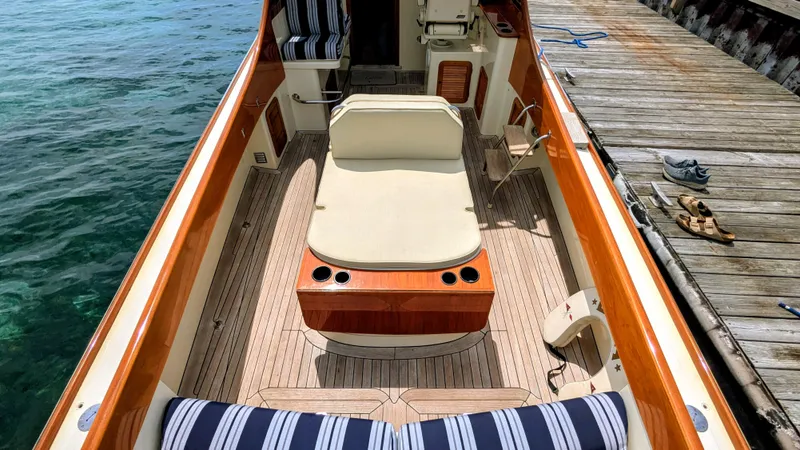 Slide: The Image of 2000 Hinckley Picnic Boat interior with striped seating, dockside view, and wooden deck. - 3