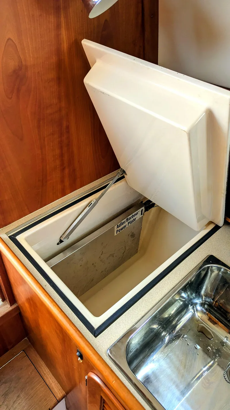 Slide: The Image of Hinckley Picnic Boat 2000 interior with open storage compartment and stainless steel sink. - 9