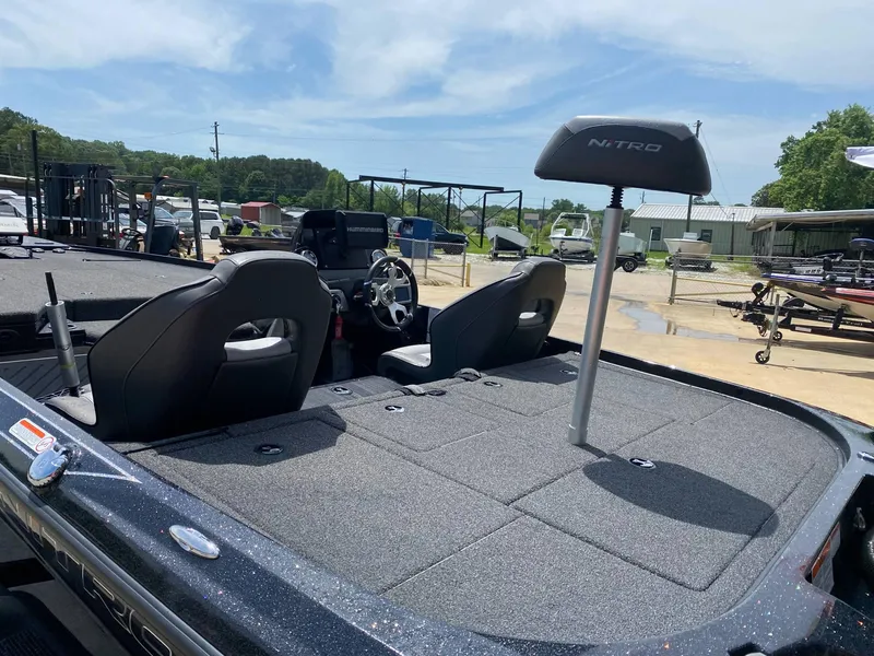 Slide: The Image of 2024 Nitro Z20 Pro boat interior with seating and steering wheel, parked outdoors. - 8