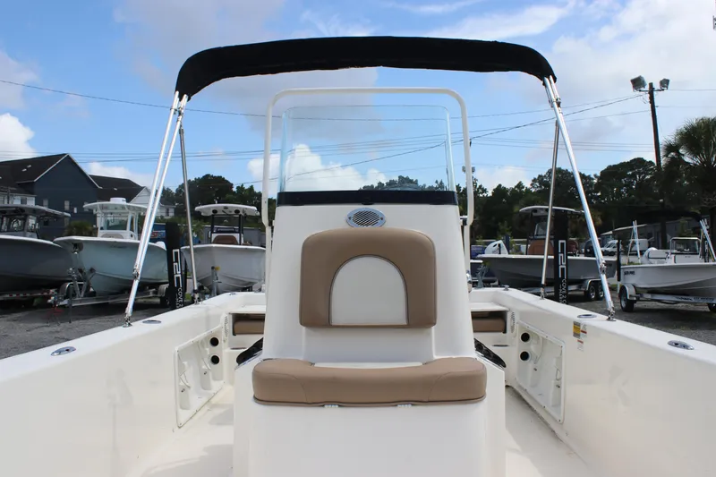 Slide: The Image of 2022 Sundance DX22 boat with canopy, beige seating, and sleek design in a marina setting. - 13