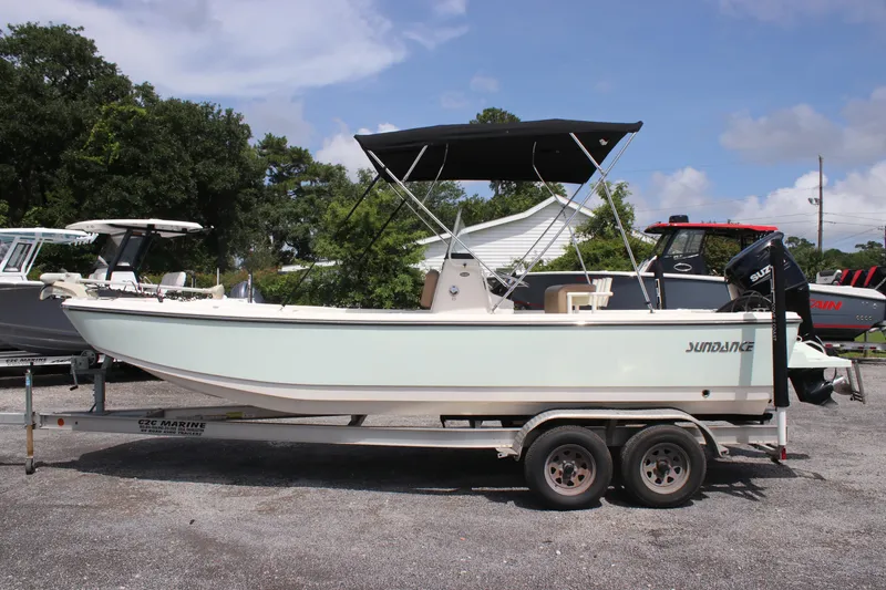 Slide: The Image of 2022 Sundance DX22 boat on trailer, parked outdoors under a clear sky. - 4