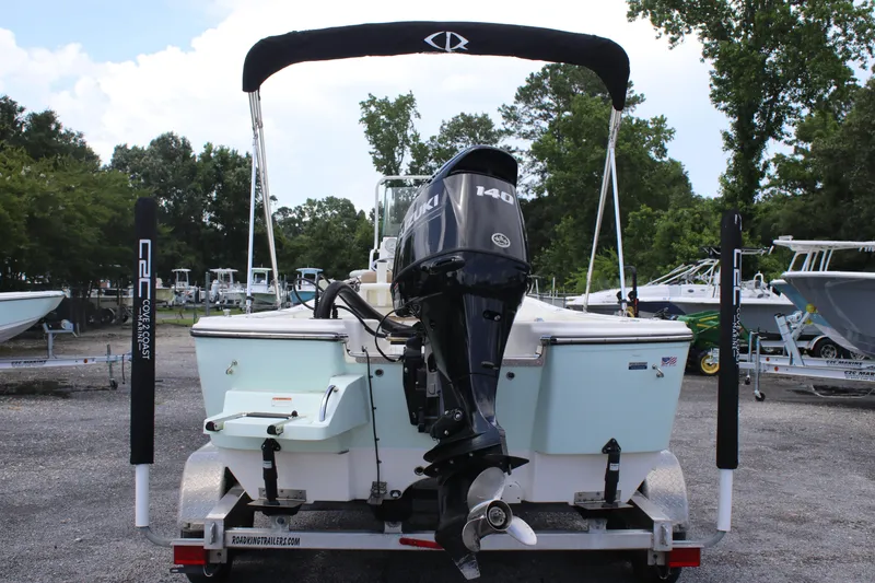 Slide: The Image of 2022 Sundance DX22 boat with outboard motor on a trailer, parked outdoors. - 5