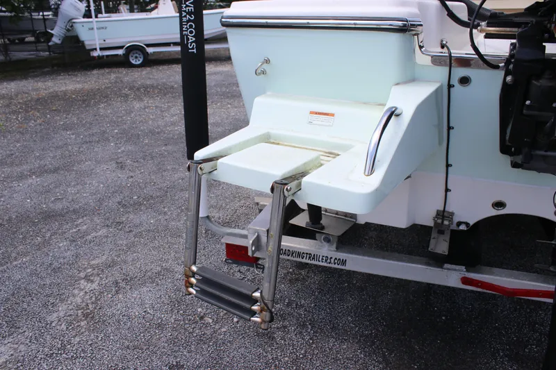 Slide: The Image of 2022 Sundance DX22 boat with a foldable swim ladder on a trailer. - 6
