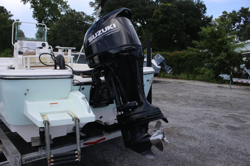 Slide: The Image of 2022 Sundance DX22 boat with Suzuki outboard motor, parked on a trailer. - 7