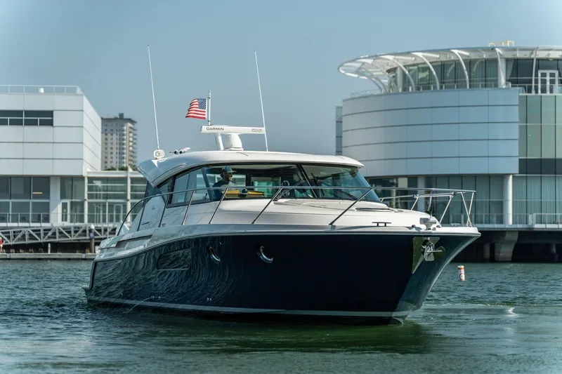 Slide: The Image of 2017 Tiara Yachts C44 Coupe cruising near modern waterfront buildings. - 15