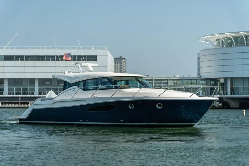 Slide: The Image of 2017 Tiara Yachts C44 Coupe cruising near modern waterfront buildings. - 20