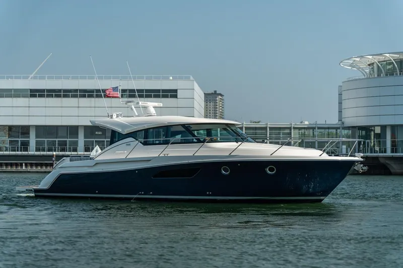 Slide: The Image of 2017 Tiara Yachts C44 Coupe cruising near modern waterfront buildings. - 21