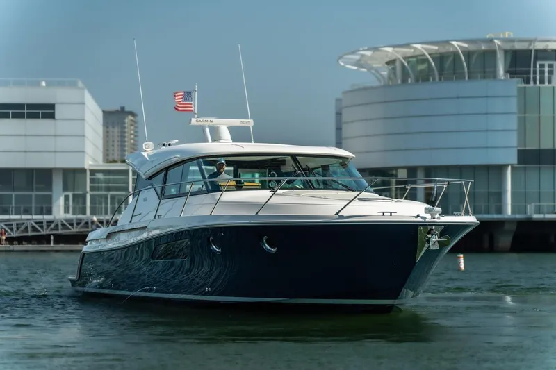 Slide: The Image of 2017 Tiara Yachts C44 Coupe cruising near modern waterfront buildings. - 23