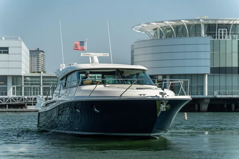 Slide: The Image of 2017 Tiara Yachts C44 Coupe cruising near modern waterfront buildings. - 24