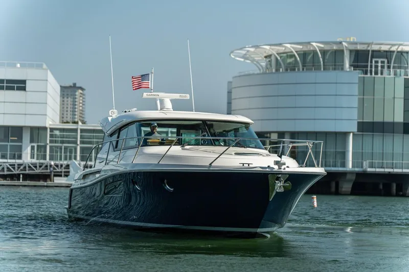 Slide: The Image of 2017 Tiara Yachts C44 Coupe cruising near modern waterfront buildings. - 25