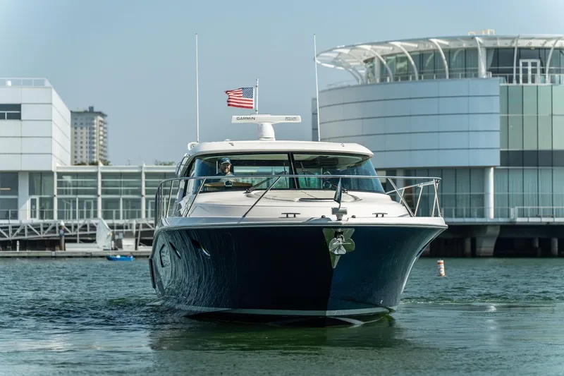 Slide: The Image of 2017 Tiara Yachts C44 Coupe cruising near modern waterfront buildings. - 26