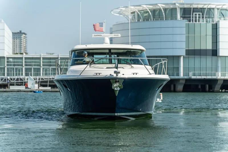 Slide: The Image of 2017 Tiara Yachts C44 Coupe cruising near modern waterfront buildings. - 27