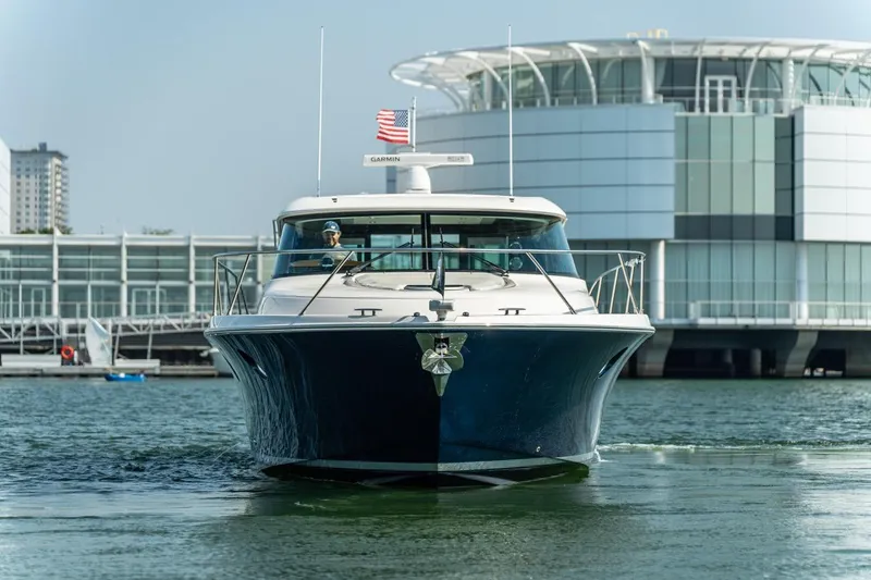 Slide: The Image of 2017 Tiara Yachts C44 Coupe cruising near modern waterfront architecture. - 28