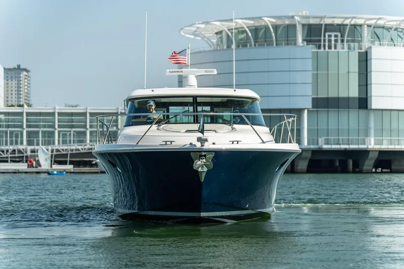 Slide: The Image of 2017 Tiara Yachts C44 Coupe cruising near modern waterfront building. - 29