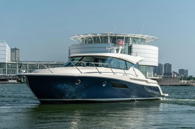 Slide: The Image of 2017 Tiara Yachts C44 Coupe cruising near modern waterfront architecture. - 32