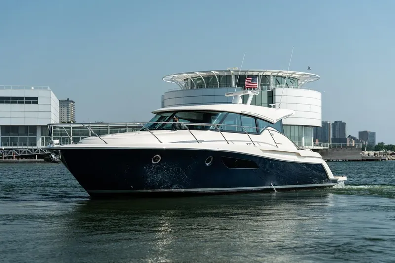 Slide: The Image of 2017 Tiara Yachts C44 Coupe cruising near modern waterfront buildings. - 33