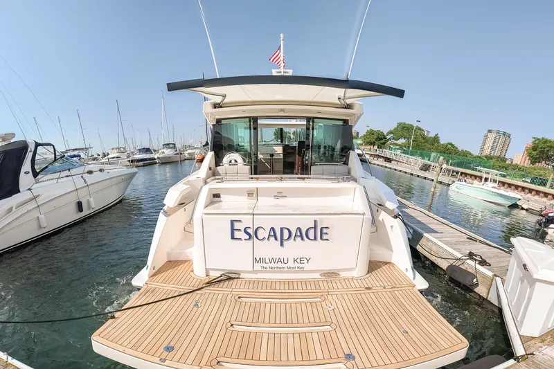 Slide: The Image of 2017 Tiara Yachts C44 Coupe docked at marina, rear view with "Escapade" name. - 39