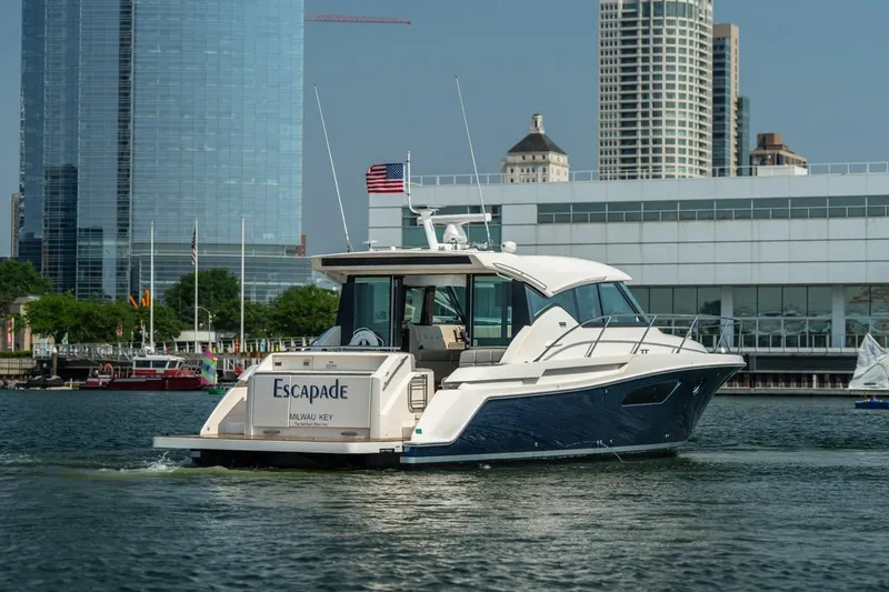 Slide: The Image of 2017 Tiara Yachts C44 Coupe cruising near city skyline, displaying "Escapade" on the stern. - 6