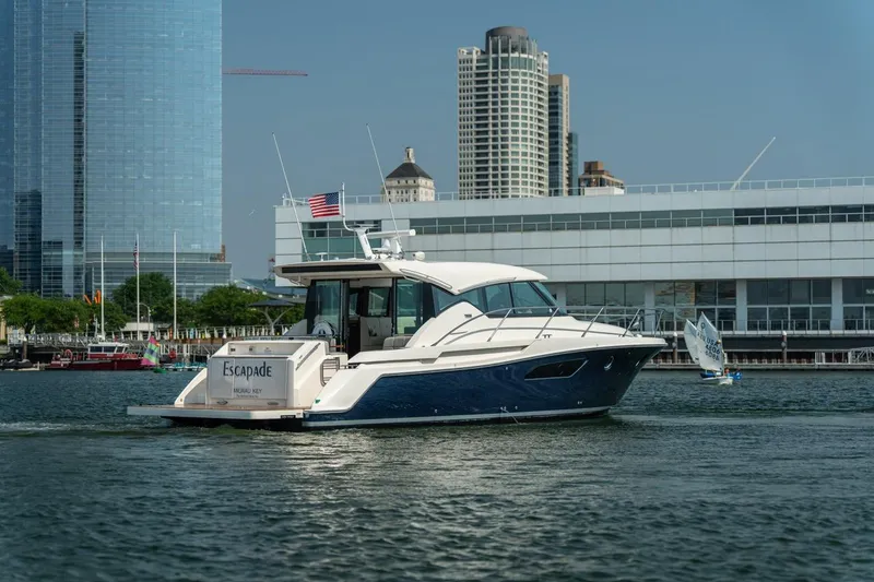 Slide: The Image of 2017 Tiara Yachts C44 Coupe cruising near city waterfront with modern buildings. - 8