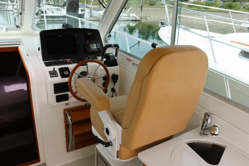 Slide: The Image of 2020 Back Cove 34O helm with tan seat, steering wheel, and navigation controls. - 13