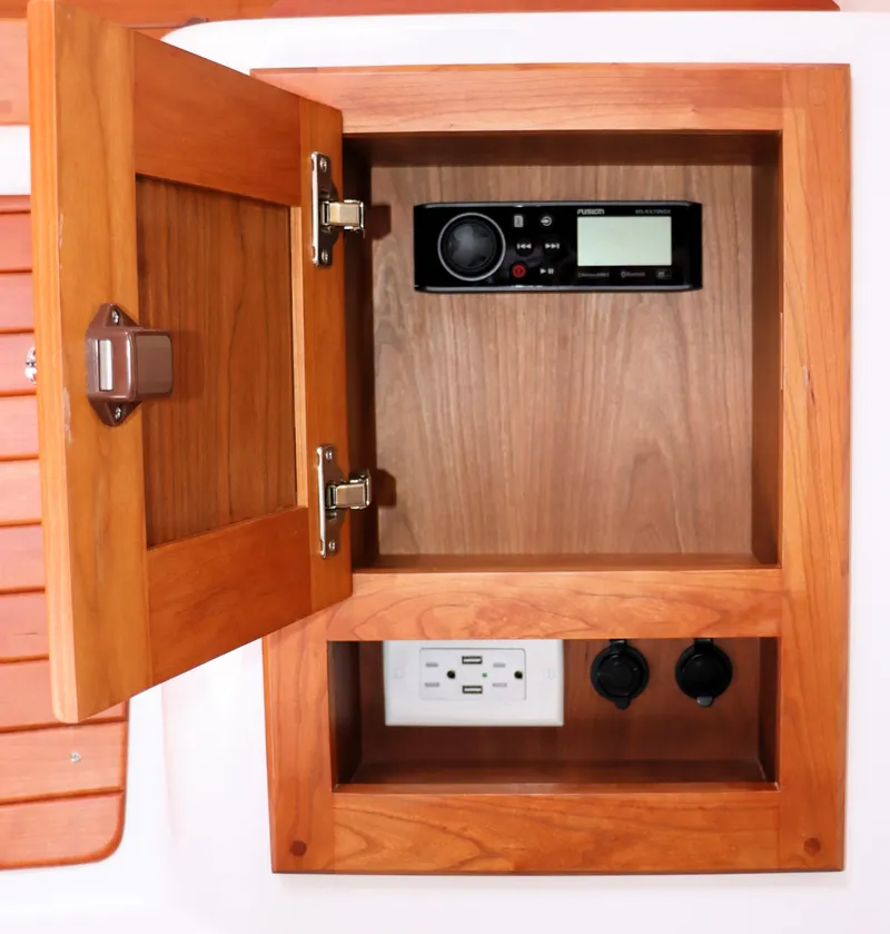 Slide: The Image of Wooden cabinet with open door, revealing a stereo system and electrical outlets on a 2020 Back Cove 34O. - 27