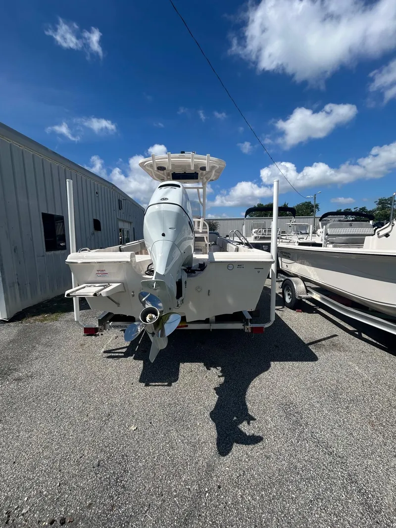 Slide: The Image of 2025 Carolina Skiff 21 Ultra Elite boat, rear view, parked outdoors under blue sky. - 10