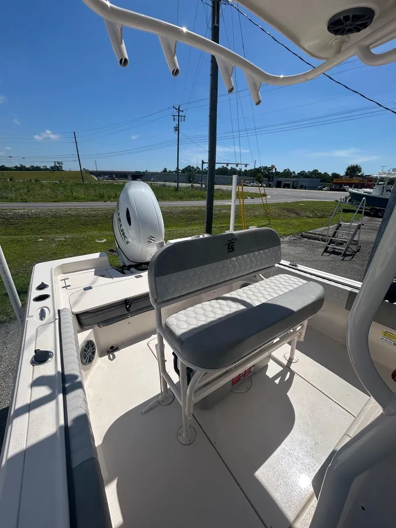 Slide: The Image of 2025 Carolina Skiff 21 Ultra Elite boat interior with seating and motor, parked outdoors. - 9