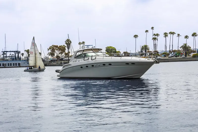 Slide: The Image of 2000 Sea Ray 510 Sundancer yacht on calm water with sailboat and palm trees in background. - 4