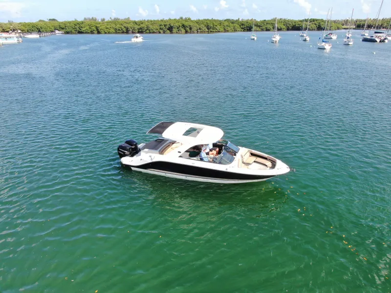 Slide: The Image of 2018 Sea Ray 310 SLX boat cruising on a serene lake with other boats nearby. - 1