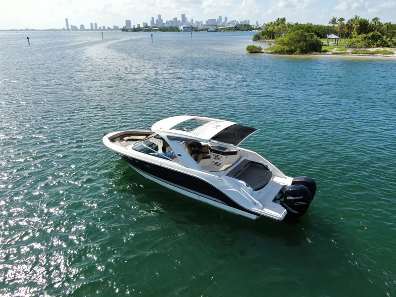 Slide: The Image of 2018 Sea Ray 310 SLX boat cruising on a sunny day near a city skyline. - 11