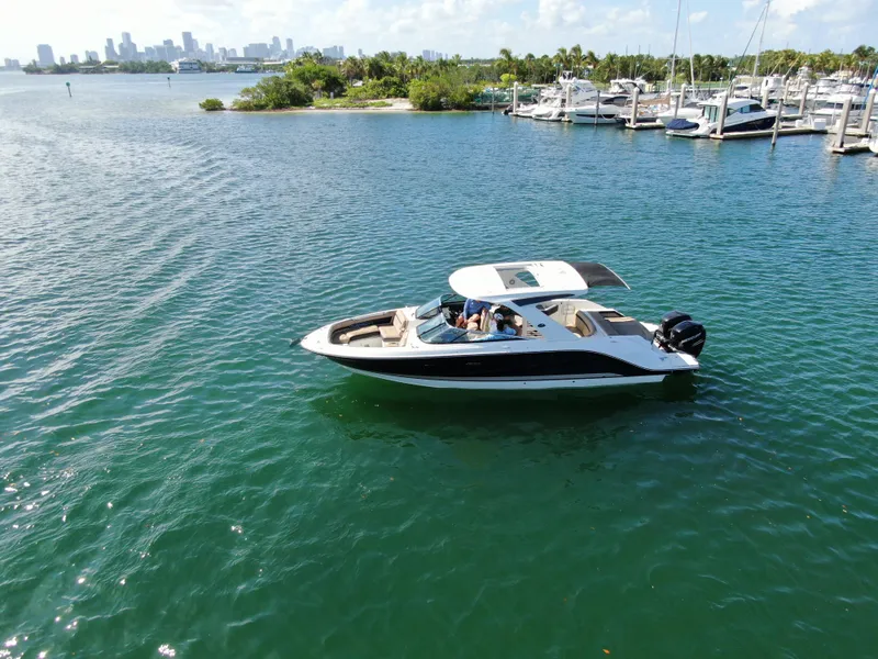 Slide: The Image of 2018 Sea Ray 310 SLX boat cruising on a scenic waterfront with marina backdrop. - 2