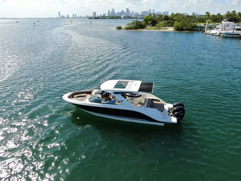 Slide: The Image of 2018 Sea Ray 310 SLX boat cruising on a sunny day near a city skyline. - 3