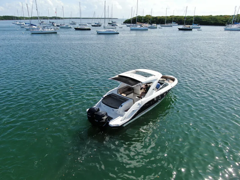 Slide: The Image of 2018 Sea Ray 310 SLX boat on calm water with sailboats in the background. - 5