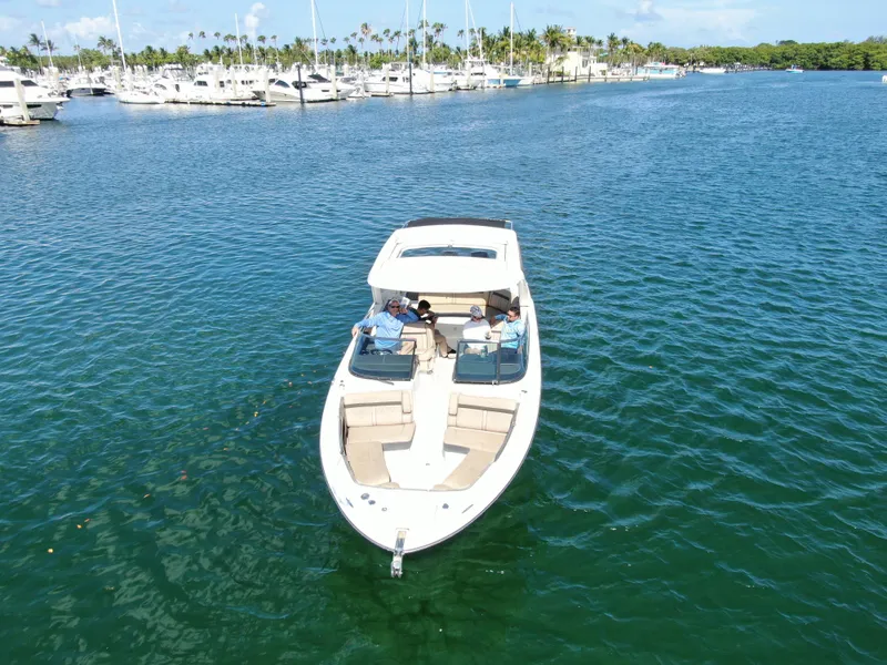 Slide: The Image of 2018 Sea Ray 310 SLX boat cruising in a marina with people onboard. - 8