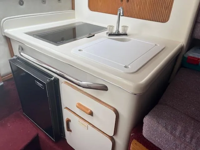 Slide: The Image of 1992 Sea Ray 310 Amberjack boat kitchenette with sink, stove, and mini fridge. - 13