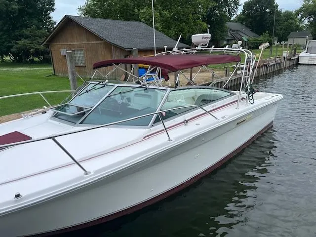 Slide: The Image of 1992 Sea Ray 310 Amberjack boat docked by a wooden house, featuring a maroon canopy. - 4