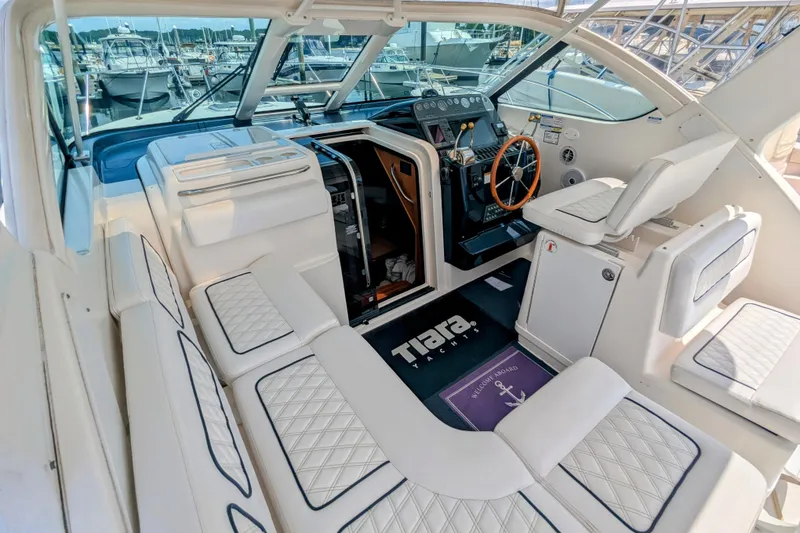 Slide: The Image of 2005 Tiara Yachts 3200 Open cockpit with white seating and helm, docked at marina. - 10